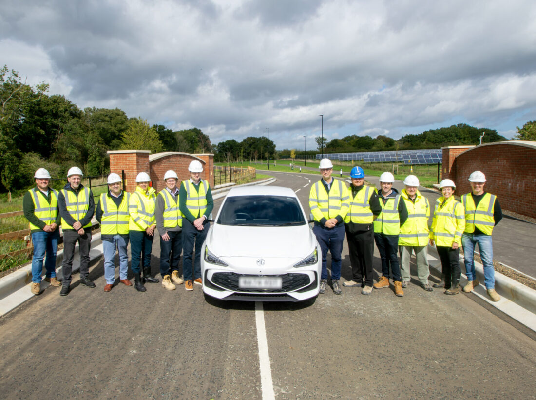 white car in the middle of a new road with construction staff wearing hi-vis white car in the middle of a new road with construction staff wearing hi-vis