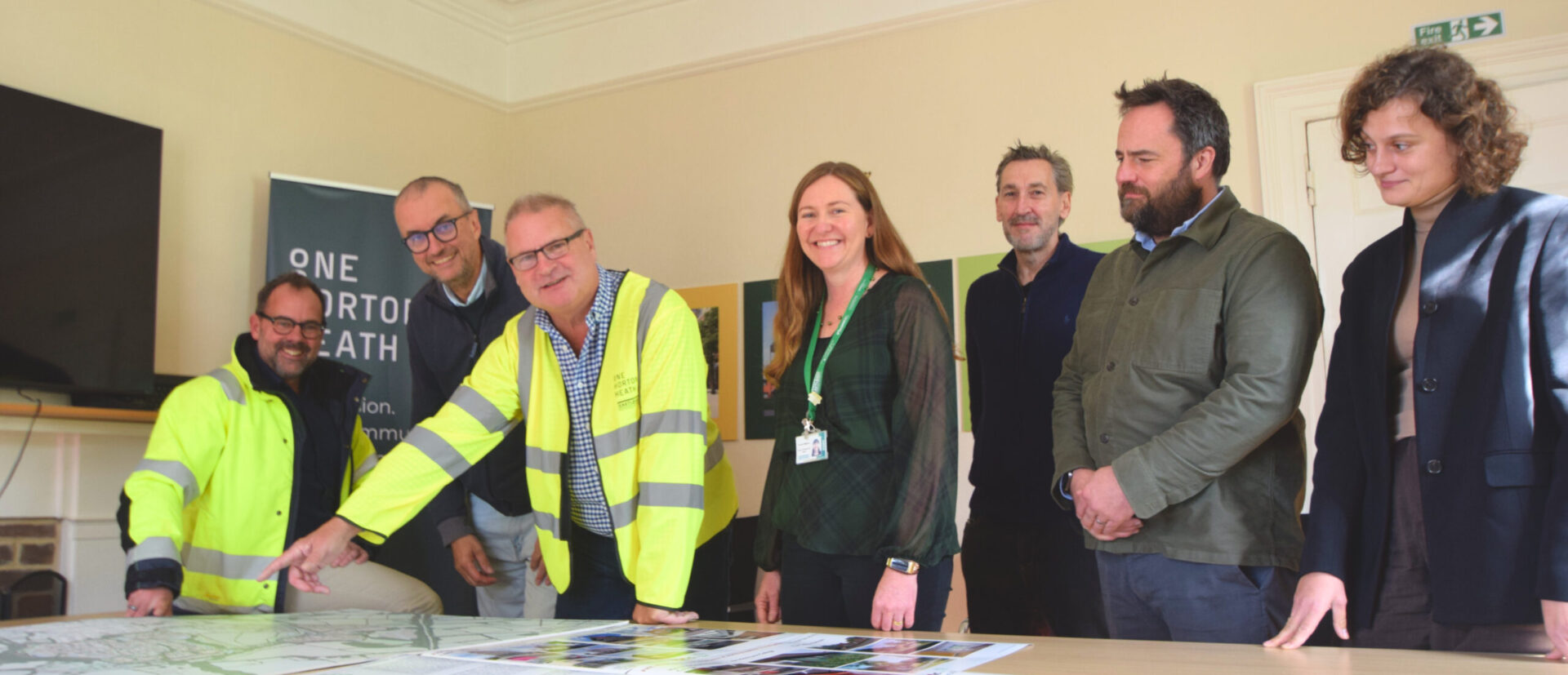 a group of people looking at building plans around a table