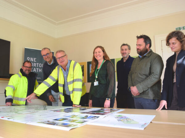 a group of people looking at building plans around a table