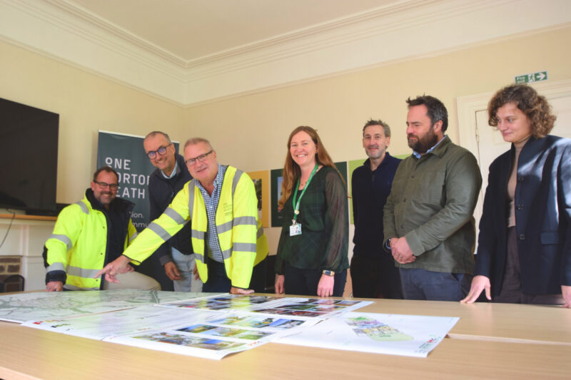 a group of people looking at building plans around a table