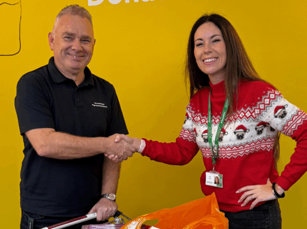 Landscape Image - a man and a lady shaking hands with a donated trolly of food donations