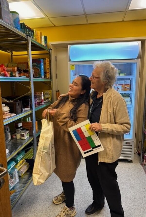 2 women looking at food on the shelves at The Food Centre (food bank)