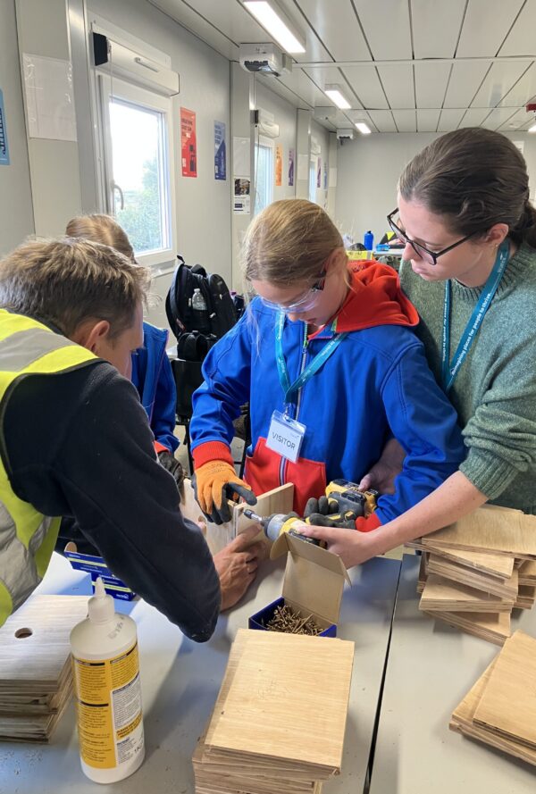 Girl Guide and staff helping to make a bird box