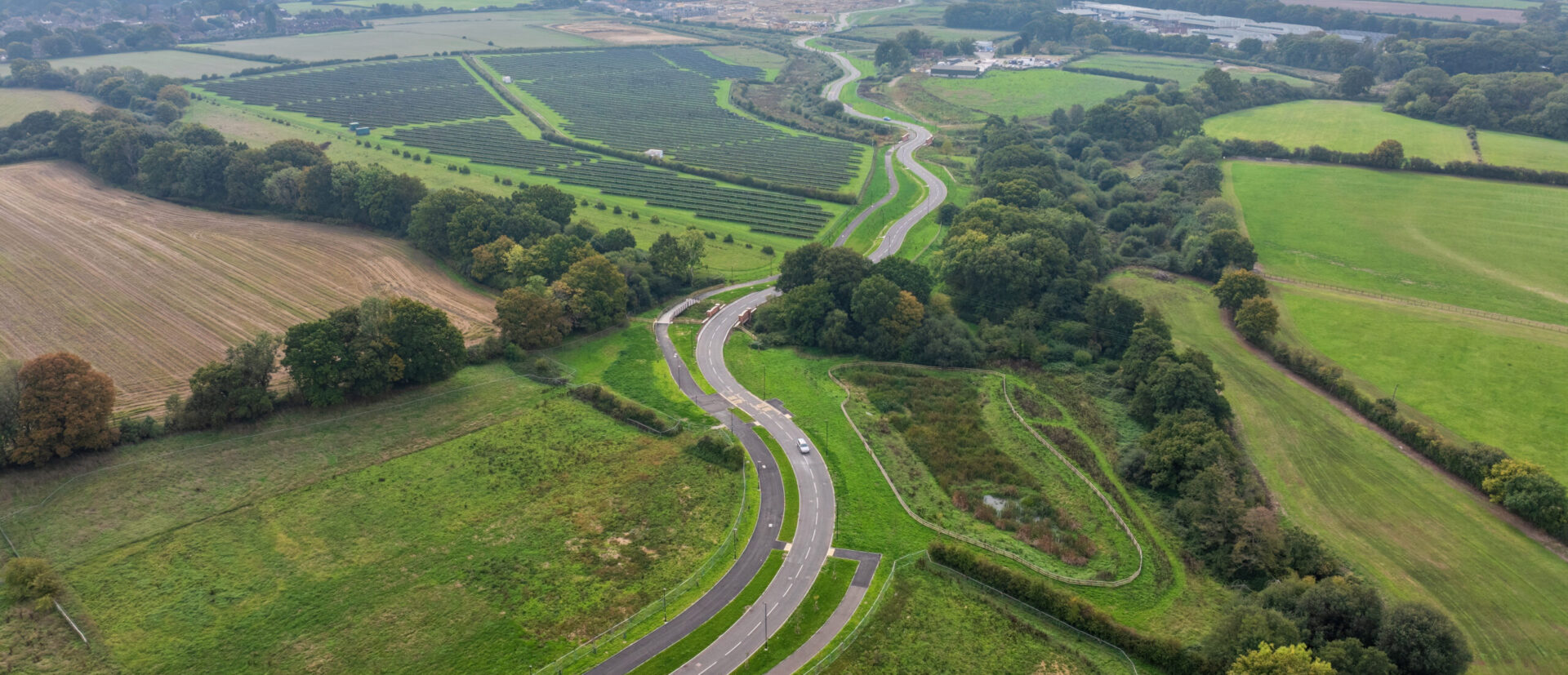 A winding road through fields with a solar farm and hedgerows