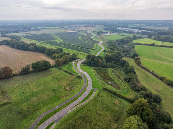 A winding road through fields with a solar farm and hedgerows