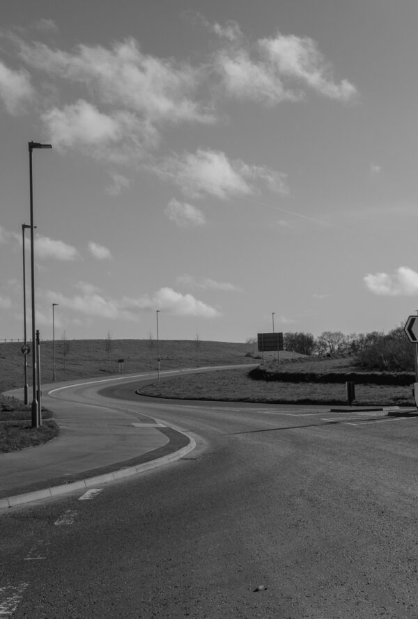 Black and white image of a winding road from Burnetts Lane, to Chalcroft way, with street lamps and green spaces at One Horton Heath