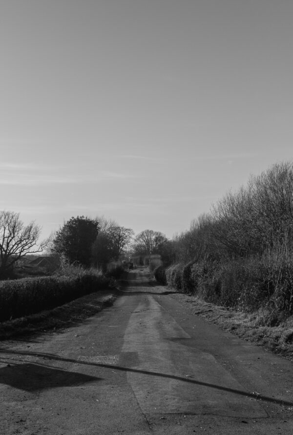 Black and white image of a an old road and 2 telegraph poles near One Horton Heath