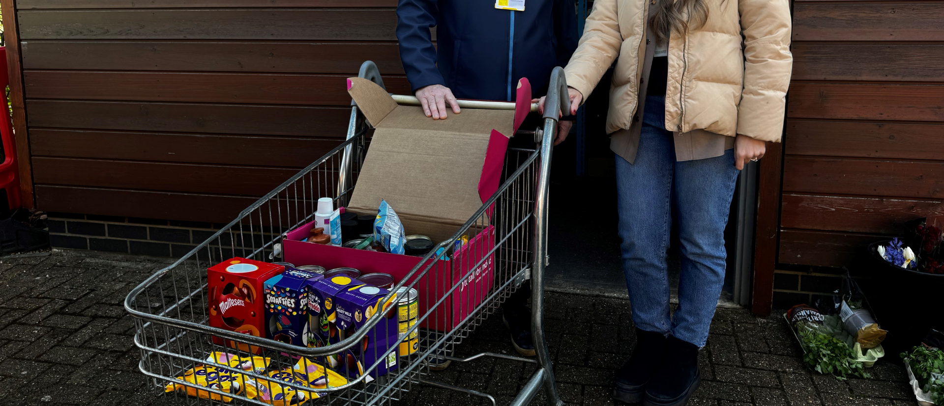 two people with a trolley of donations for a charity, ay Easter
