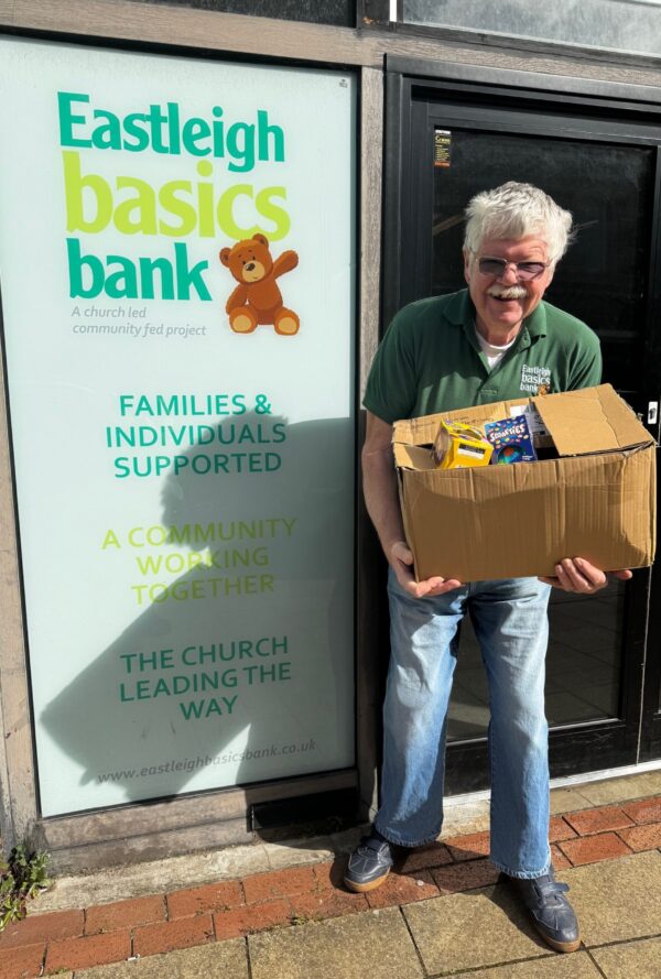Man holding a box of donated easter goods in front of Eastleigh Basics Bank Centre