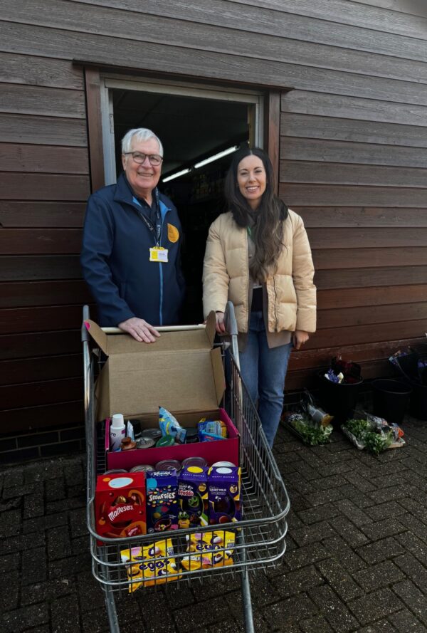 2 people in front of a trolley of donated easter goods