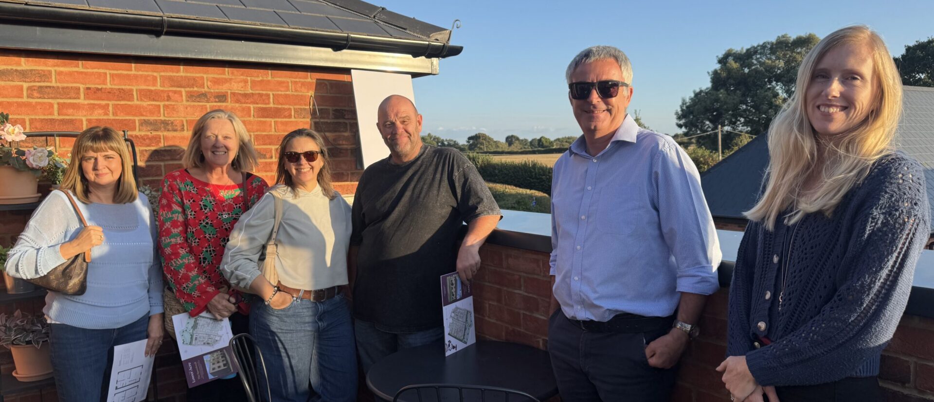 Parish council representatives standing on a balcony in the sun smiling